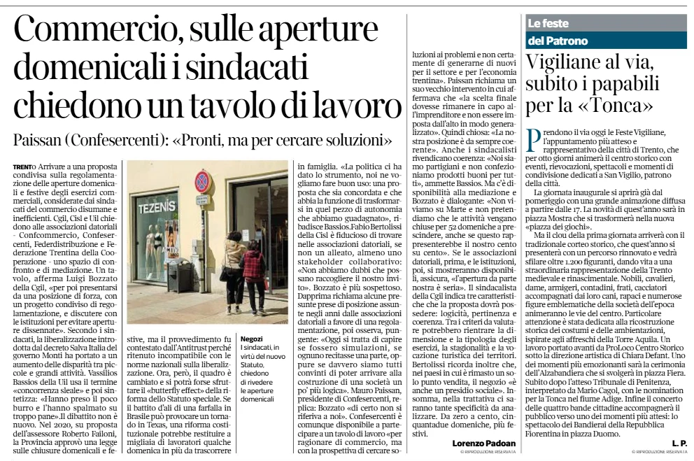 Limmagine mostra pagine di giornale con diversi articoli e titoli ben visibili riguardanti il commercio e una festa patronale, e include una fotografia di due persone che osservano la vetrina di un negozio.