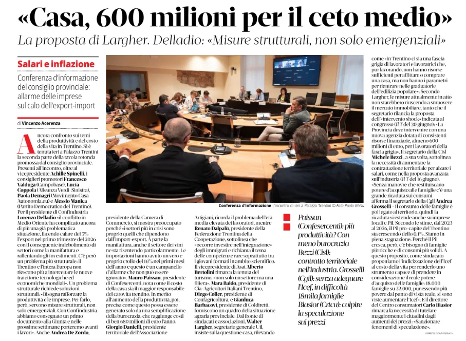 La fotografia ritrae una riunione in cui diverse persone sono sedute attorno a un grande tavolo in una sala, con uno schermo che mostra delle immagini sulla parete di fondo.